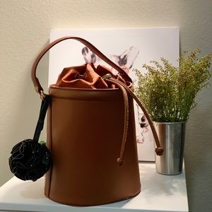 Crossbody leather bucket bag with pendant detail